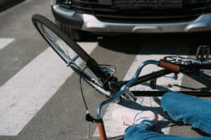 A cyclist hit by a cardwith the Bike lying on the ground.