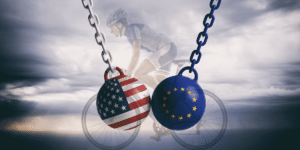 A Bike in the background of the US and EU flag superimposed on a wrecking ball.